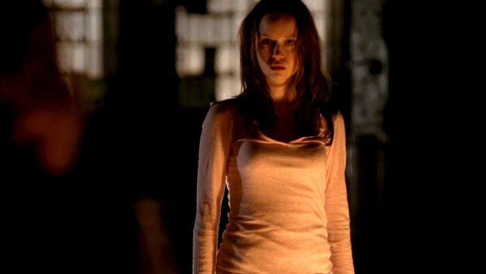 Cameron in a warehouse illuminated by a fire off screen in The Sarah Connor Chronicles