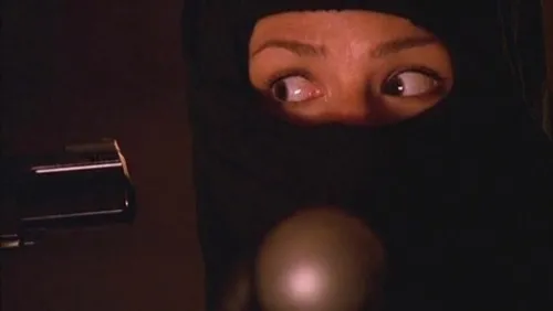 Sy'ds eyes peek through a dark mask, with the tip of a gun to the left of the screen