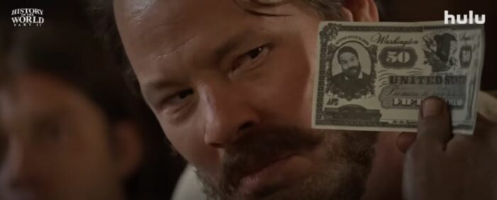 A fake $50 bill being held up to Grant's face in the History of the World Part 2 trailer