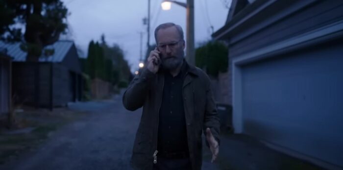 Bob Odenkirk walks down a dim street with a phone to his ear in Lucky Hank