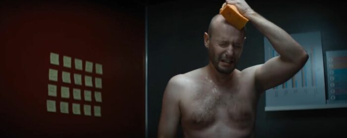 Ian makes a pained face while holding a sponge to his bald head