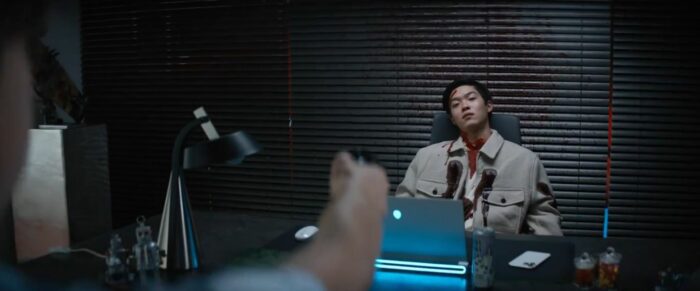 Sang Woo in his chair with bloody bulletholes on his torso