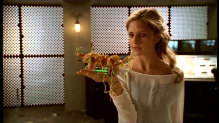 Buffy, empowered by a spell, holds the glowing uranium core in her hand after killing Adam in 'Primeval'