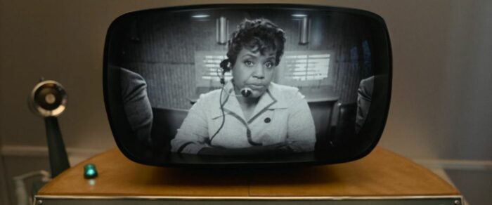 Shirley in black and white on a small screen, wearing a headset