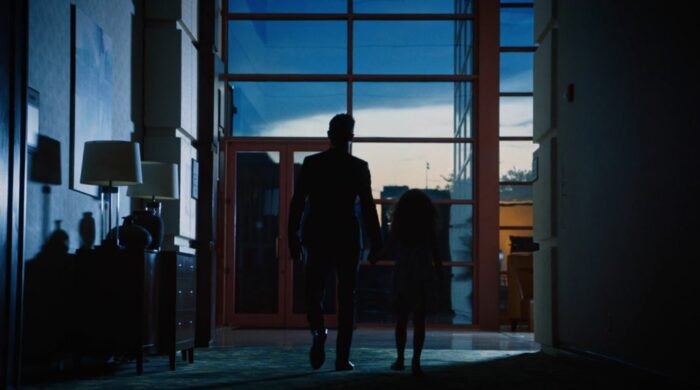 A silhouette of Kevin holding the hand of little girl Patti as they exit the hotel