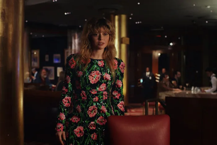 Charlie standing in a dark room wearing a floral dress
