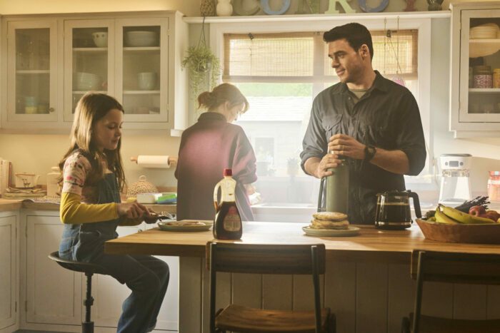 Mason in a sunlit kitchen with his wife and daughter
