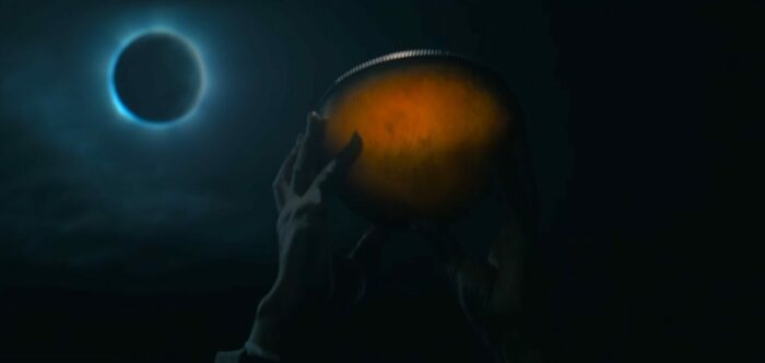 Mrs. Davis S1E3 - The glowing Holy Grail is held aloft by a pair of hands, solar eclipse showing in the background