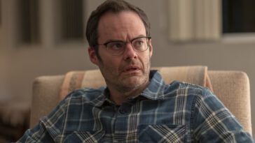 Barry as Clark, wearing glasses and looking up from a chair