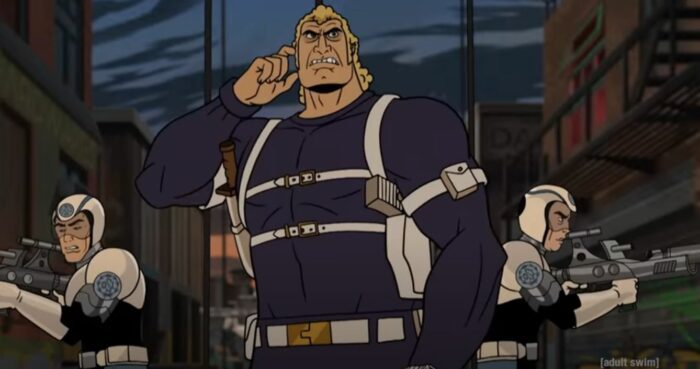 Brock Samson puts a hand to his ear with soliders to each side of him in a shot from the trailer for the Venture Bros movie