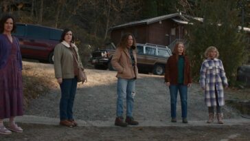 Nat (Juliette Lewis), Shauna (Melanie Lynskey), Tai (Tawny Cypress), Van (Lauren Ambrose), and Misty (Christina Ricci) stand in a row in front of cars and a building in the woods in Yellowjackets S2E6, "Qui"