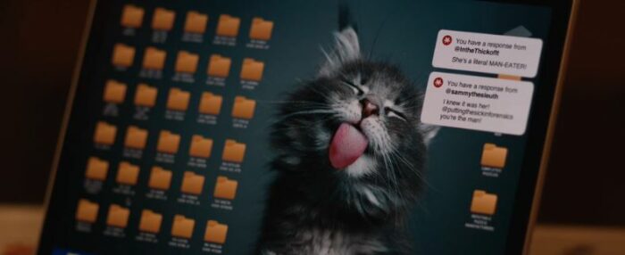 A computer screen features a cat with its tongue stuck out. Two messages to the left: Response from @inthethickofit "She's a literal MAN-EATER!"; Response from @sammythesleuth "I knew it was her! @puttingthesickinforensics you're the man!"