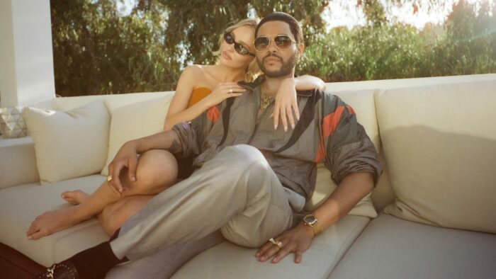 Abel Tesfaye plays Tedros and Lily-Rose Depp plays Jocelyn in The Idol. In this shot, they lounge together on an outdoor couch at Jocelyn's mansion. 