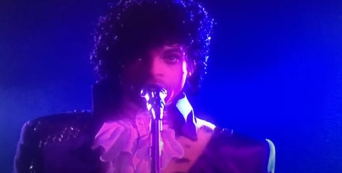 Prince singing into a microphone in Purple Rain