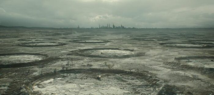 Numerous circles on dusty ground with a city skyline in the distance