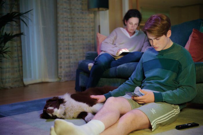 Season 1 Episode 6: L-R Olivia Colman as Nick Nelson's mom and Nick Nelson (Kit Connor) in their living room.