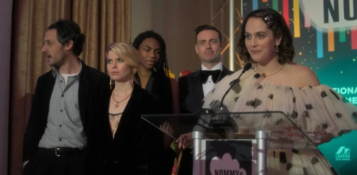 Tiffany stands on stage with her colleagues accepting her award. 