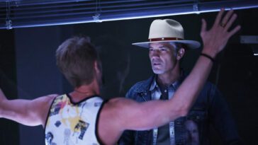 Clement with his back to the camera and his hands against glass as Raylan looks at him from the other side in Justified: City Primeval Episode 3, "Backstabbers"