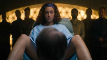 Foundation S2E7 - Sareth lies on an examination table, legs spread with a doctor between her legs, a gallery of onlookers standing behind her
