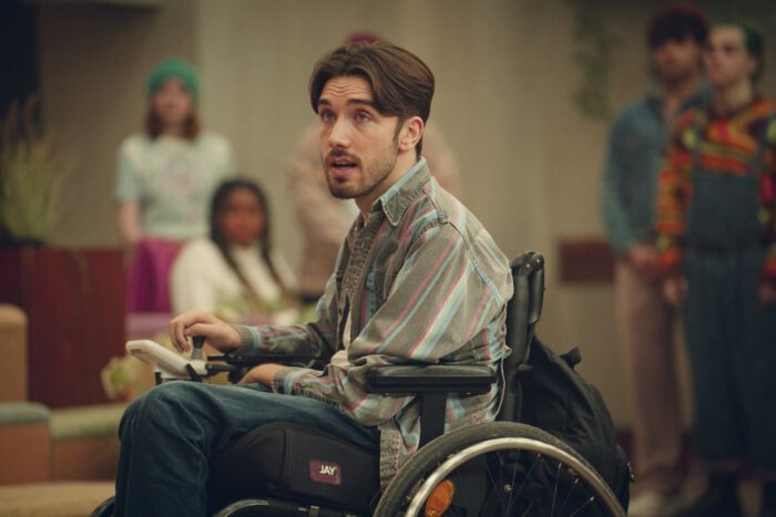 Sex Education Season 4 Episode 7. George Robinson as Isaac Goodwin in the main foyer inciting the sit-in for disability rights. 
