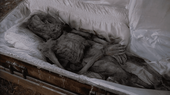 A dessicated and strange-looking corpse inside an open coffin