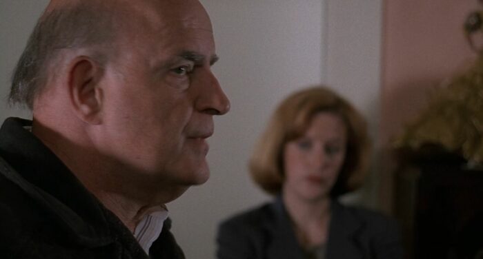 Clyde Bruckman in profile as Scully looks on in the background