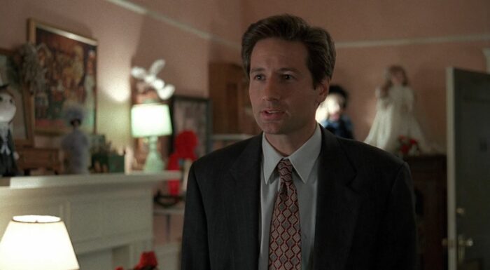 Mulder in a room with white walls with dolls in it