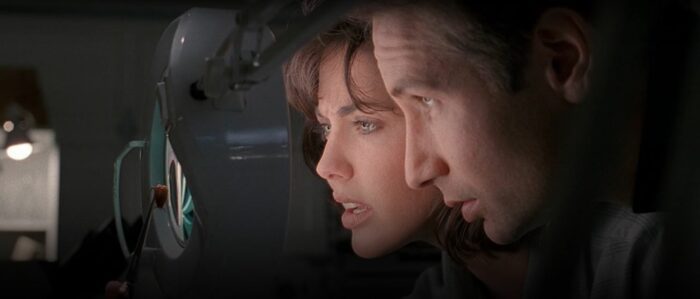 Mulder and Bambi's faces close together as they look at a roach specimen