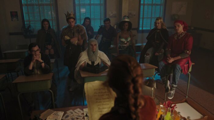 Characters in costume sit in a classroom in Riverdale