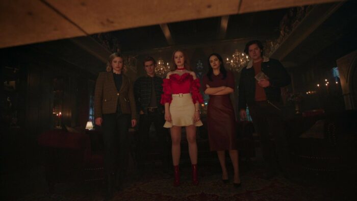 The characters in Riverdale stand in a room looking on ominously