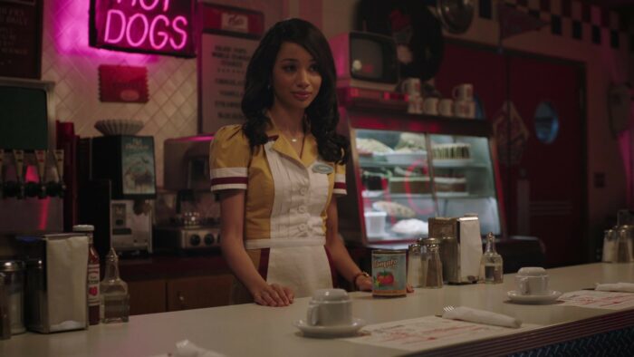 A young woman stands behind a diner counter