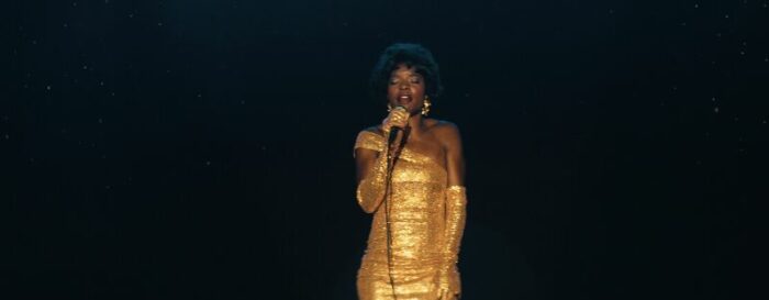 A young Lillian singing, wearing a gold dress