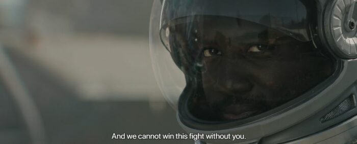 Trev looks on, in a spacesuit, while a subtitle reads "And we cannot win this fight without you"