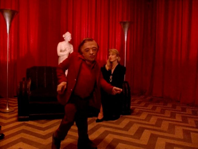The Man from Another Place dances in the Red Room as Laura Palmer sits on a couch in the background