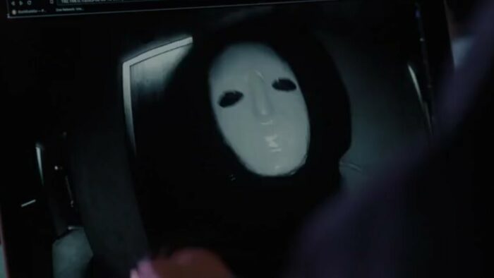 A Murder at the End of the World S1E2 - Zoom in on a laptop screen showing a doorcam image of a figure in a black cloak and a white mask
