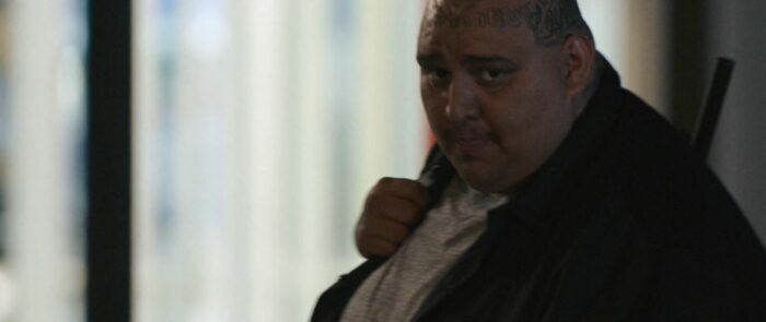 Fernando with a gun over his shoulder in the last shot of The Curse S1E3, "Questa Lane"