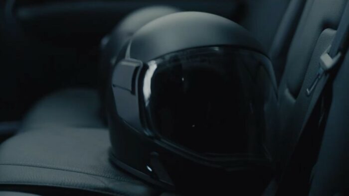 A Murder at the End of the World S1E4 - Two black spacesuit helmets sit beside each other in the backseat of a car