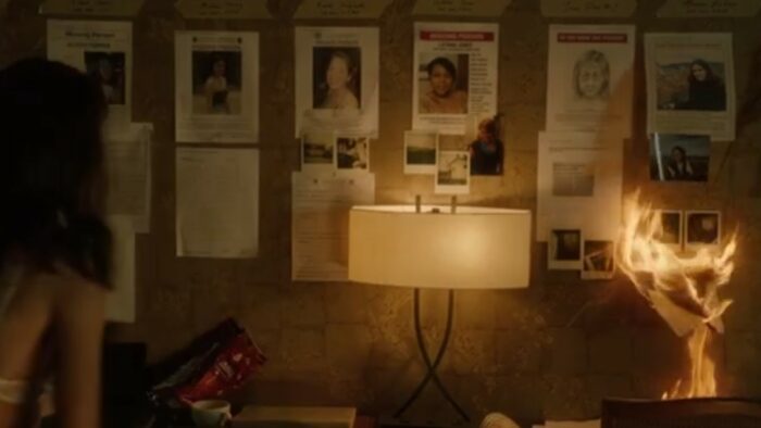 A Murder at the End of the World S1E5 - The wall of a motel room, covered in pictures, some catching on fire as young Darby stares in horror
