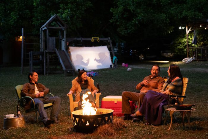 People sit in chairs around a fire