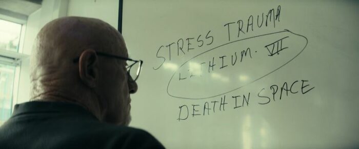 Henry in front of a whiteboard that lists stress trauma, lithium 7, and death in space