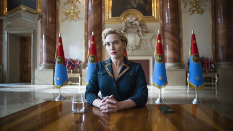 Kate Winslet sits at a table in The Regime on HBO