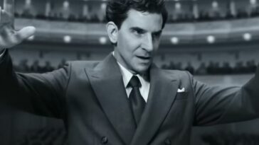 Bradley Cooper as Leonard Bernstein in Maestro, conducting an orchestra, in black and white