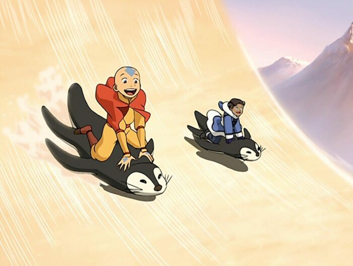 Aang and Katara riding penguins down a large incline