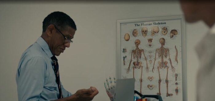 Dr. Vickers in his office, standing by a skeleton poster
