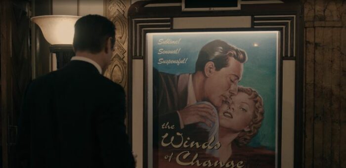 Sugar looks at a poster for a film called The Winds of Change